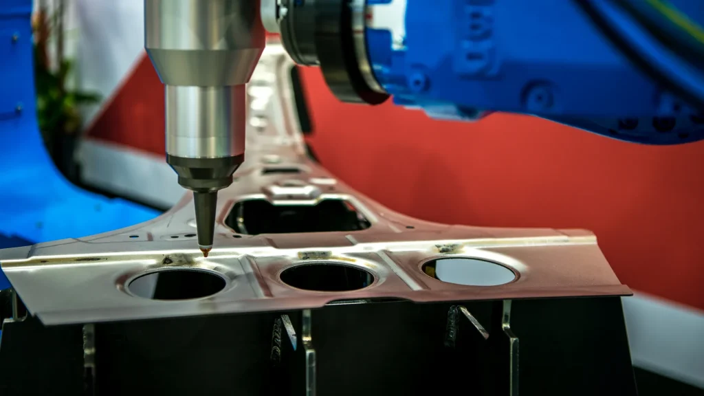 Brazo robótico perforando una pieza automotriz comparando la precisión de troquelado vs estampado de metal.
