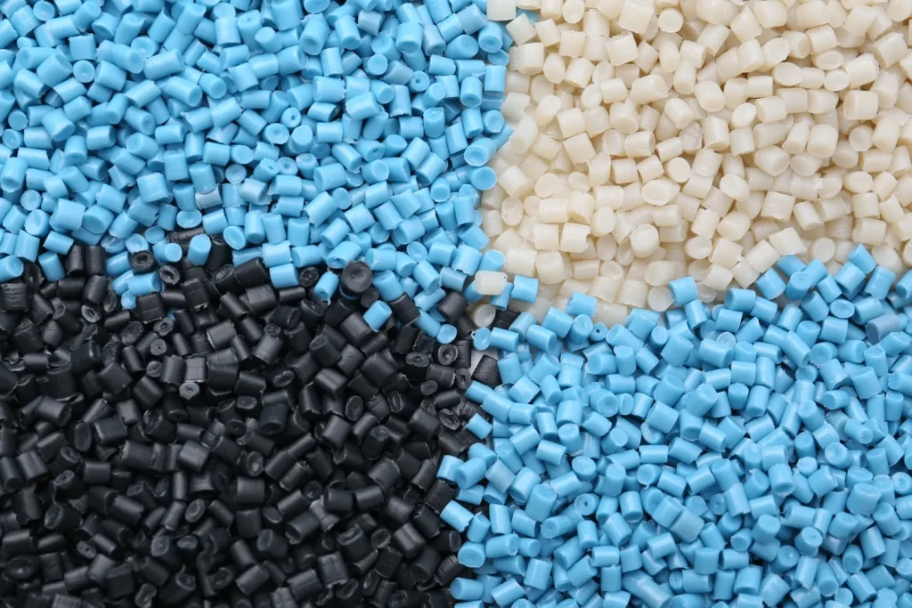 Cuatro secciones de gránulos industriales de diferentes colores representando varios tipos de plástico en pellet.